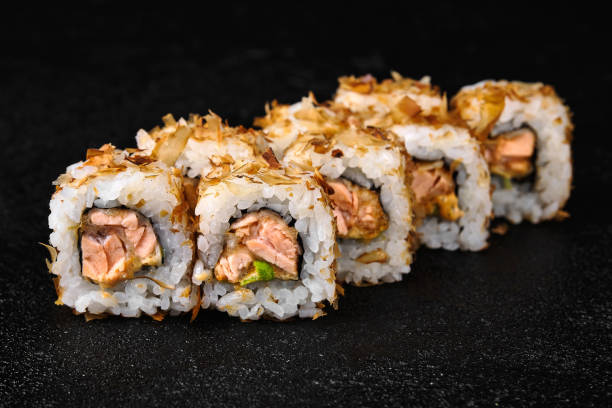 istock Sushi roll with baked salmon on black background 1456551636