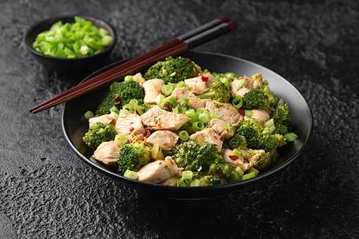 Stir fried Chicken and Broccoli in black bowl.