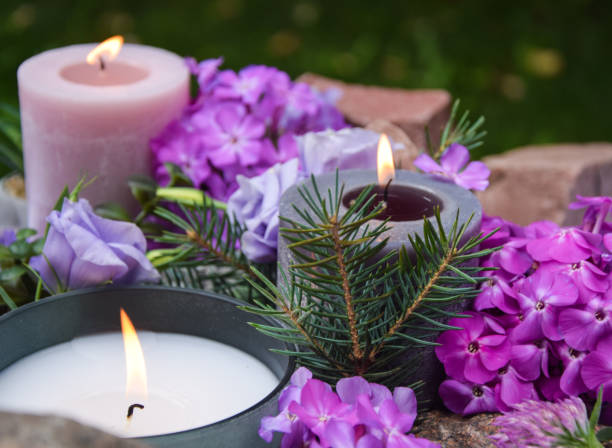 Top angle view burning candles purple flowers stone blurred background Top angle view burning candles purple flowers stone on blurred background. Focus on light candlewick. Beautiful composition with violet candles for spa treatment. Zen relax memorial concept. pink memorial candle with flowers stock pictures, royalty-free photos & images