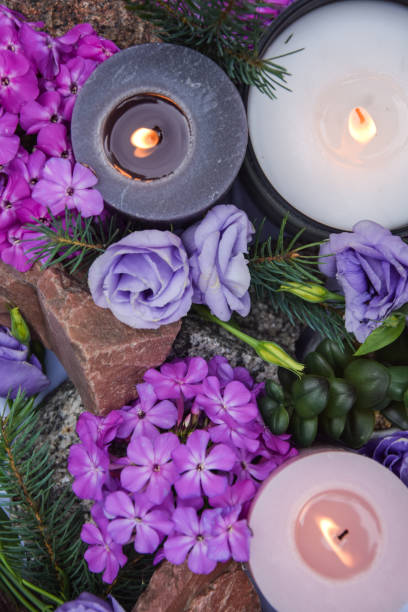 Table top view burning candles purple flower stone green plant outdoor Table top view burning candles purple flowers stone with pine branches green plant outdoor. Light candlewick. Beautiful composition with violet candles for spa treatment. Zen relax memorial concept. pink memorial candle with flowers stock pictures, royalty-free photos & images