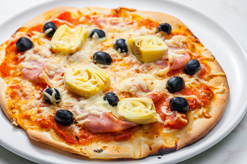 pizza with ham, black olives and artichokes