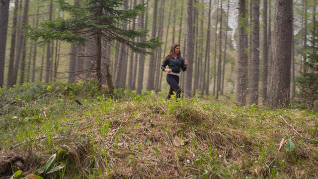 Woman jogging outdoors in nature through forest