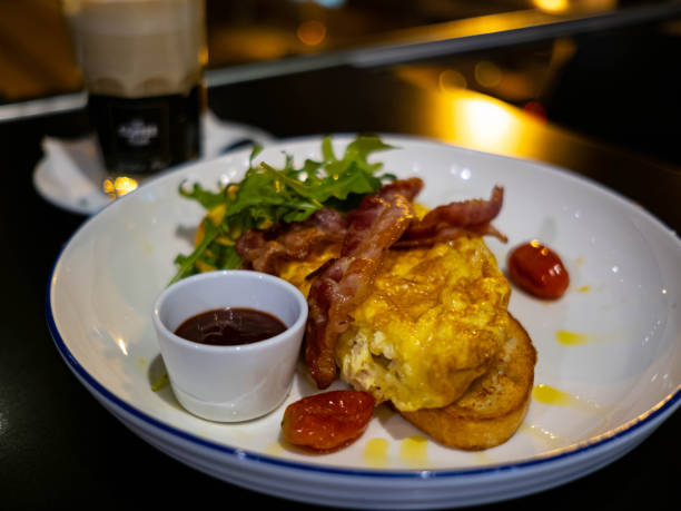 istock Omelet bread with bacon on top and small fried tomato beside in white plate , there is bokeh in the background 1456554609