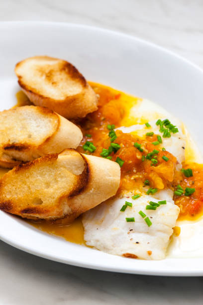 istock white fish with tomato sauce and roasted baguette slices 1456554896
