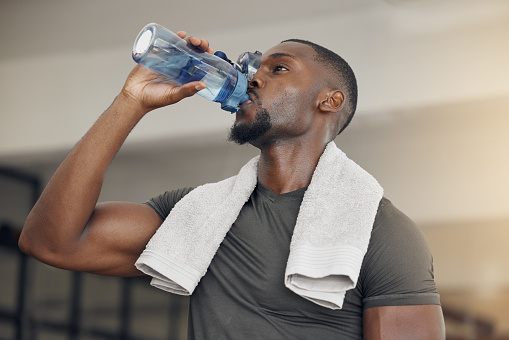 Fitness, gym and black man drinking water after workout or training for hydration, health or wellness. Strong, healthy and African athlete enjoying a beverage after intense exercise at sports center.