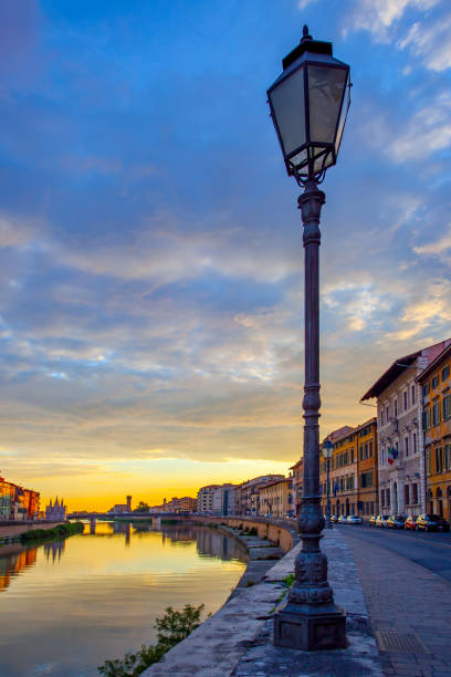 View of PIsa with Arno river, beautiful sky at sunset and vintage street light, Italy
