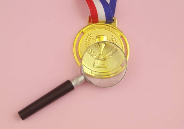 istock Gold medal and magnifying glass on pink. 1456557742