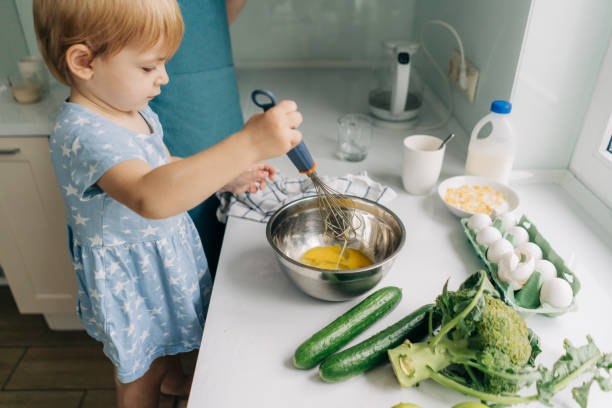 istock Toddler little daughter helps mom cook dinner. 1456561144