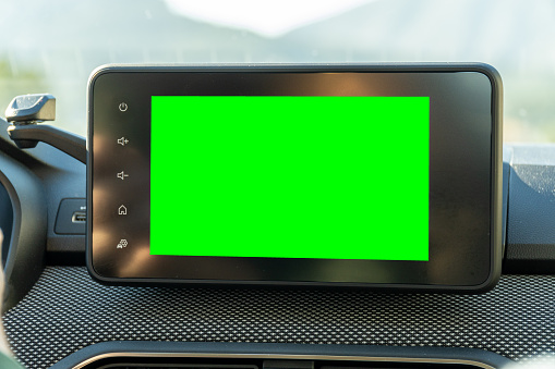 Close-up of multimedia screen with chroma key green background, inside a modern car