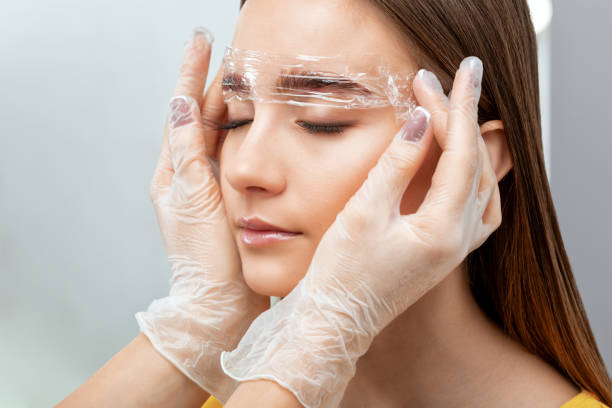 der visagist stylt die augenbrauen der augenbrauen lang und färbt die augenbrauen. augenbrauen-laminierung. professionelles make-up und gesichtspflege. - removing tweezing eyebrows eyebrow caucasian stock-fotos und bilder