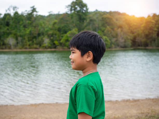 um menino fica ao lado do reservatório à noite. mostra olhar para os objetivos da vida. - target standing concepts focus - fotografias e filmes do acervo