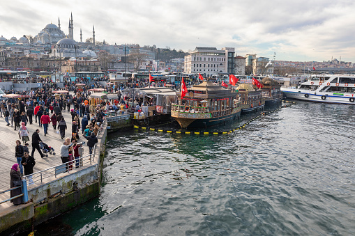 Istanbul, Turkey - Feb 01, 2019: Eminonu district with many facilities to eat such as floating restaurants and carts with fresh bakery, hot corn or roasted chestnuts in Istanbul, Turkey.