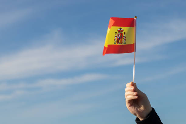 istock Spanish flag in hand flutters in the wind against the sky 1456570243