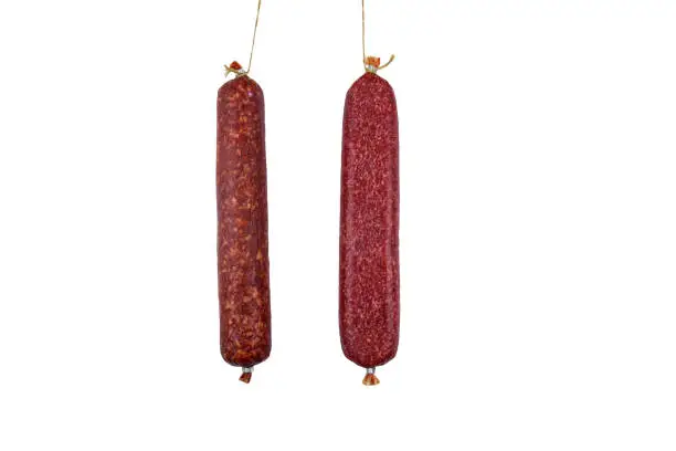 Photo of Two hanging raw smoked sausage isolated on white background