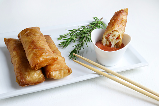 Fried spring rolls with sweet chili sauce on a white background. Asian cuisine.