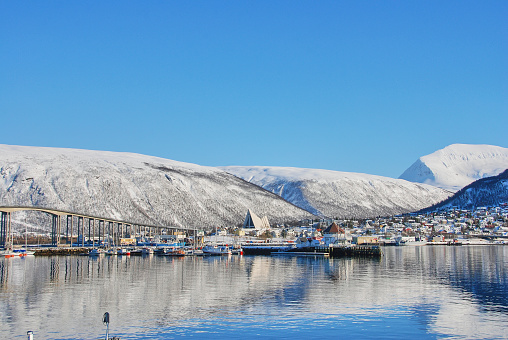 cathedral in the winter landscape of the port of Tromso in a fjord at the coastline of northern Norway with snow covered mountains in the background