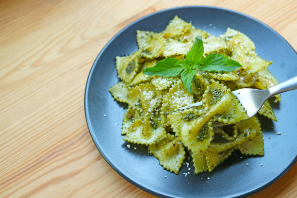 Fork Scooping Mouthwatering Farfalle or Bow-tie Pasta in Pesto Sauce
