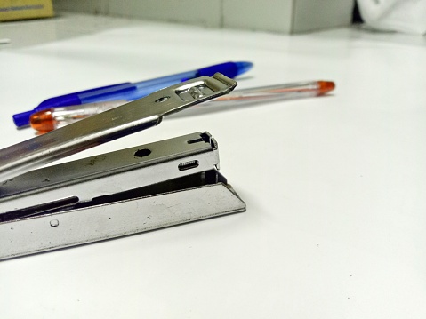 stapler and pen side by side on the white floor