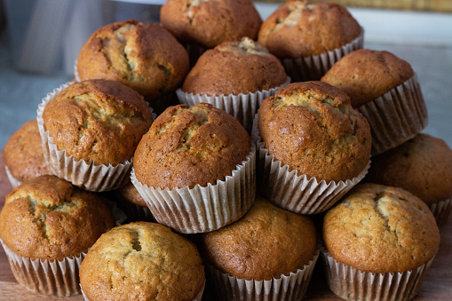 a close up of a tall pile of banana muffins with a pale parchment wrapper.