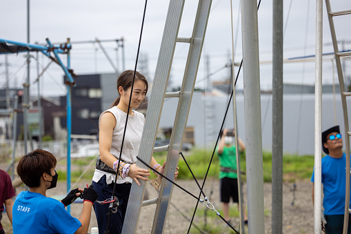 Young woman climbing up ladder for trapeze