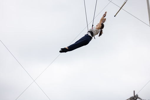 Young woman practicing trapeze and flying in the sky