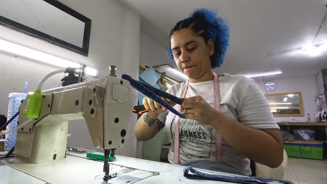 Seamstress uses the machine to make an arrangement to the garment