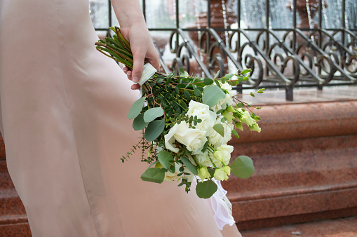 Close-up of a bride's hands holding a bouquet of flowers containing thistles and white roses