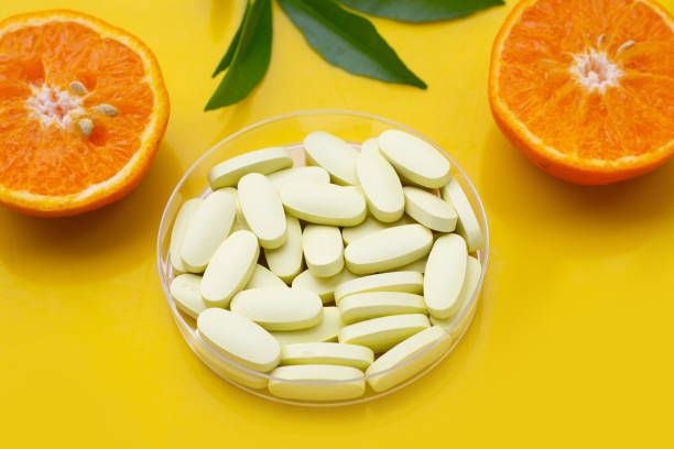 istock Vitamin C pills with  fresh orange citrus fruit on yellow background. 1456585714