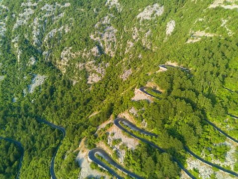Incredible winding mountain road - Lovcensky serpentine with dangerous sharp extreme turns that leads to the top of mountain range of the Montenegrin mountains covered with green vegetation