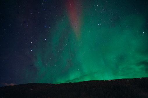 Dramatic view of majestic birght colorful Northern Lights in the wintertime above the mountain village in Scandinavia