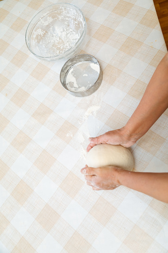 Top down view of woman kneading the dough on the table
