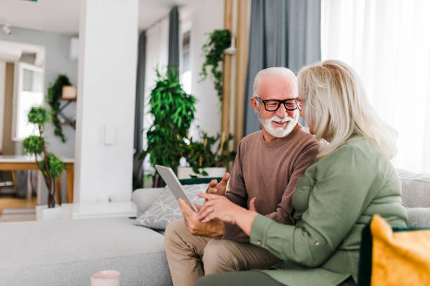 istock Senior retired couple using digital tablet and enjoy talking conversation together on sofa with happiness laugh smile and joyful at home 1456588024