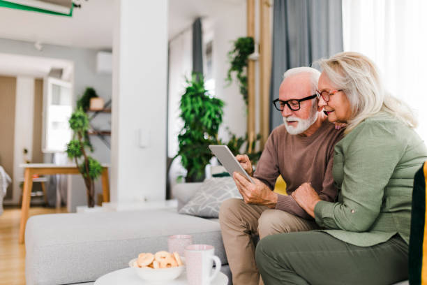 istock Senior retired couple using digital tablet and enjoy talking conversation together on sofa with happiness laugh smile and joyful at home 1456588052