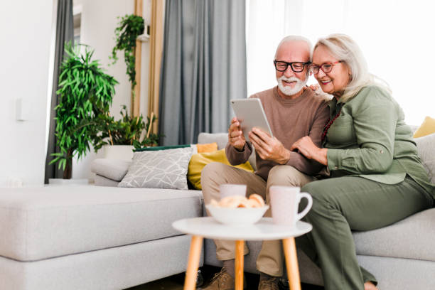 istock Senior retired couple using digital tablet and enjoy talking conversation together on sofa with happiness laugh smile and joyful at home 1456588331