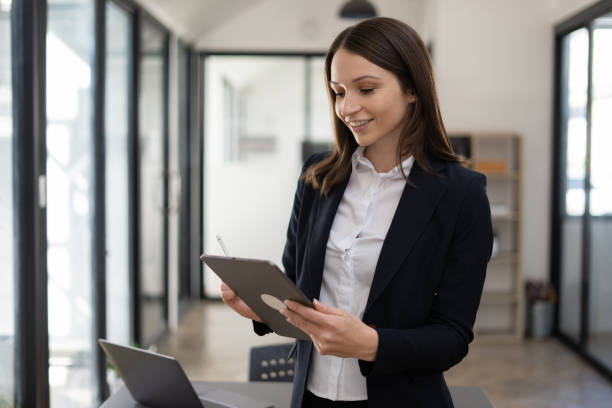istock Beauty business woman using her digital tablet while sitting on a desk in a modern startup office. 1456588410
