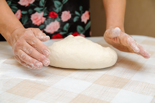 Close up shot of an unrecognizable woman wearing apron, holding a glass tray full of white sourdough starter and placing it on the table.