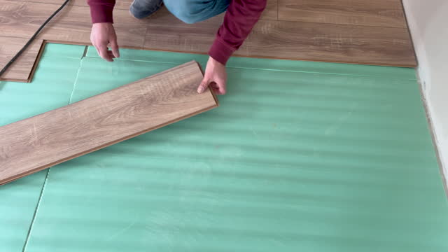Carpenter man is laying laminate wood in living room, 4K Video footage