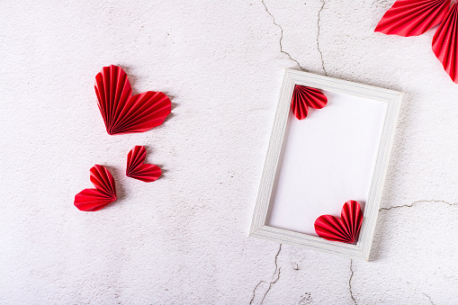 Blank photo frame and DIY paper hearts and leaves on plaster. Home decor.