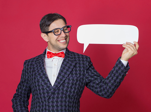 Nerd man holding a white speech bubble over pink background