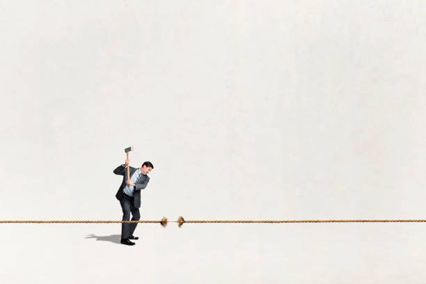 istock Man Uses Axe To Cut Long Piece Of Rope 1456593326