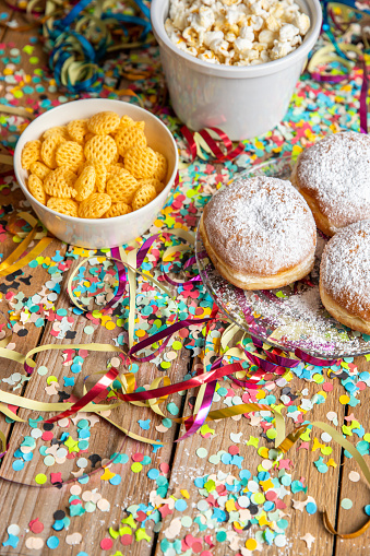 Baked pastry doughnuts Krapfen for carnival Fasching celebration with party snacks, popcorn streamers and confetti