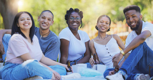 relax, summer and picnic with friends in park with beer for bonding, fun and party. nature, smile and gen z with portrait of people in countryside for happy reunion, diversity and celebration - lanche da tarde imagens e fotografias de stock