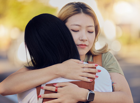 Woman, friends and love hug in city outdoors together for freedom, support and lesbian couple in street. Asian people, friendship and emotional hugging for grief or sadness in urban city street