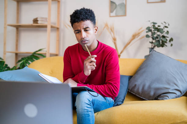 istock Focused black man working on laptop at home and taking notes 1456601222