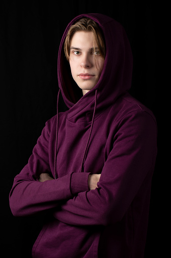 Portrait of a young man in a hoodie with a hood on a black background.Studio photo.