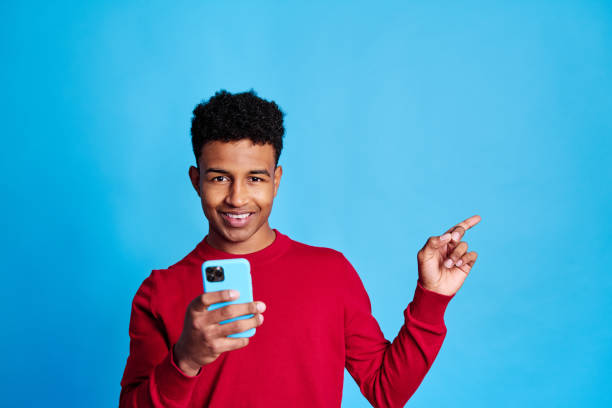 istock Cheerful black boy with smartphone pointing with a finger 1456606556