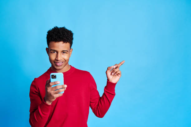 istock Cheerful black boy with smartphone pointing with a finger 1456606629
