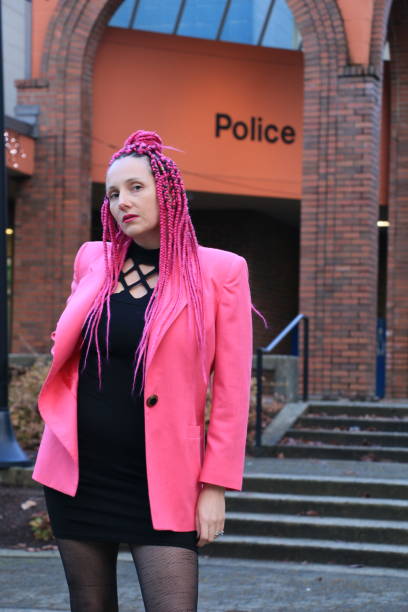 Hanging at the Police Station A Caucasian model standing outside a police station. She is wearing pink long braided hair, a pink jacket and a black mini dress with black stockings. police station canada stock pictures, royalty-free photos & images