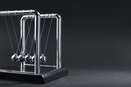 Newton's cradle on dark background, space for text. Physics law of energy conservation