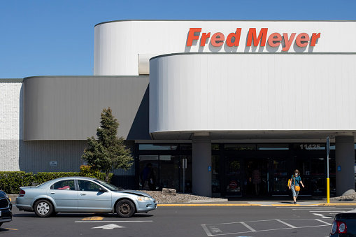 Beaverton, OR, USA - July 24, 2022: A shopper walks out of a Fred Meyer store in Beaverton, Oregon. Fred Meyer is an American chain of hypermarket superstores owned by Kroger.